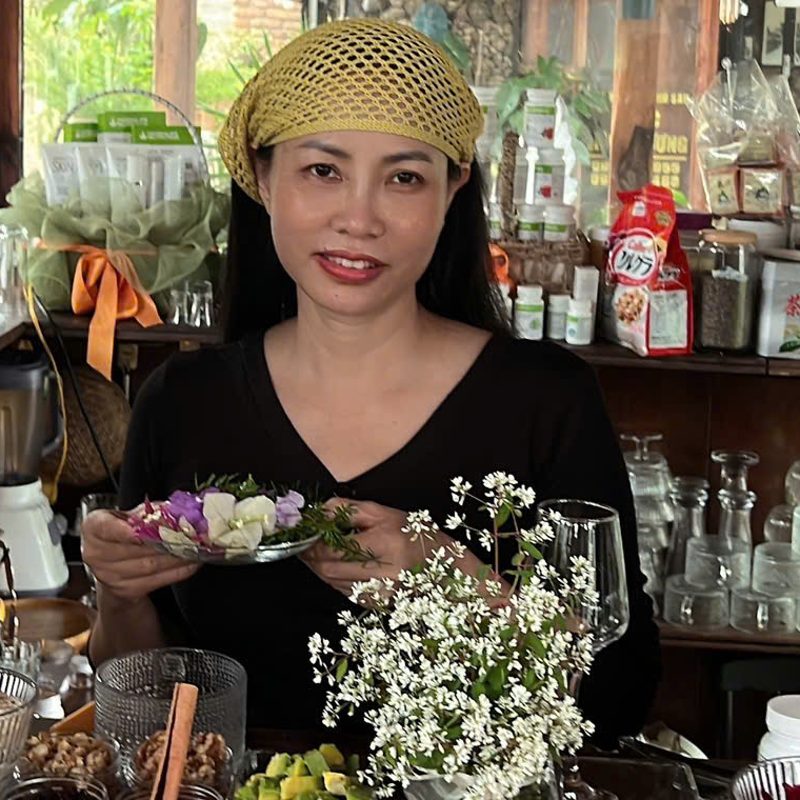 Chị Cẩm Hằng đứng sau quầy bar cầm đĩa hoa trang trí